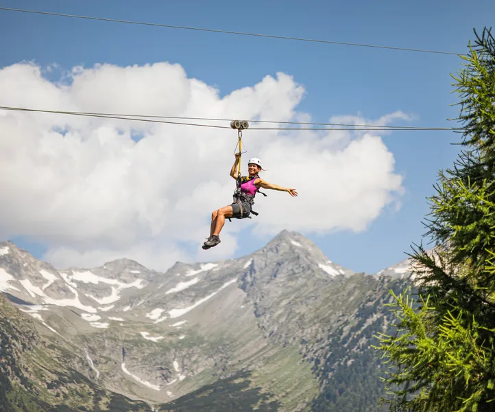 Frau am Skyglider Zipline am Klausberg vor schneebedeckter Zillertaler Alpenkette