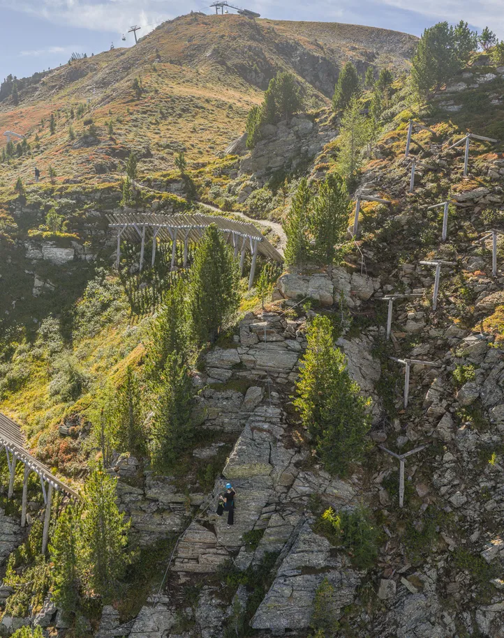 Panoramic view of Ahrntal via ferrata with climber, cable car mountain station and autumn alpine landscape