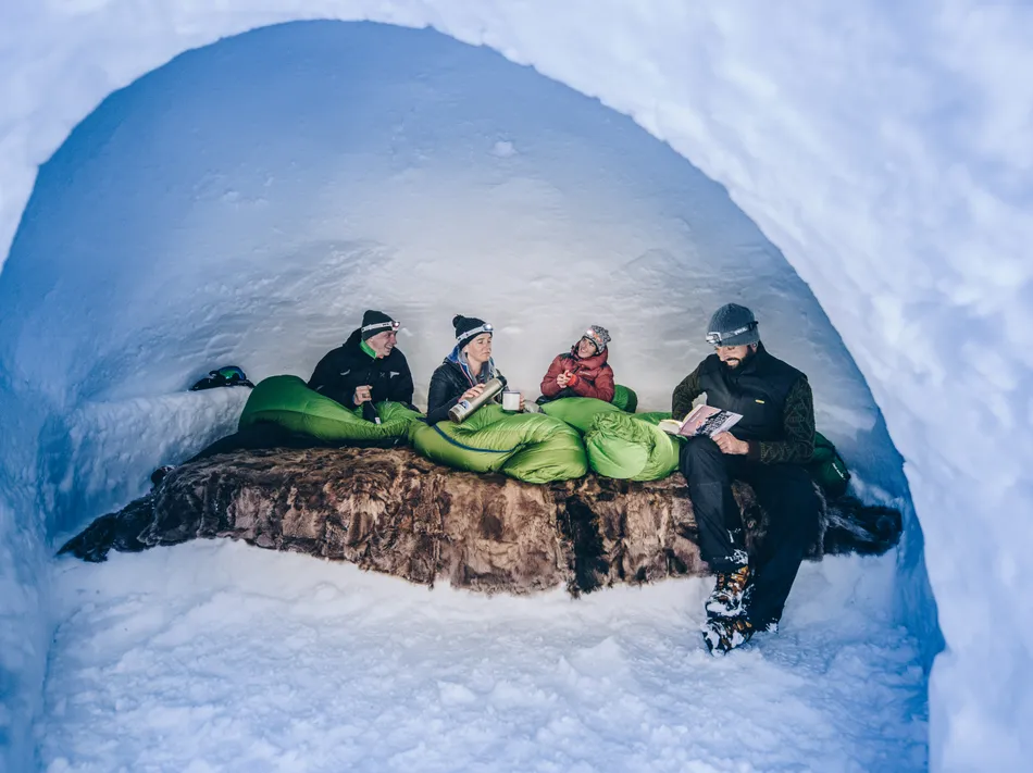 Pernottamento accogliente in igloo nella Valle Aurina – ospiti con lampade frontali in un igloo di neve