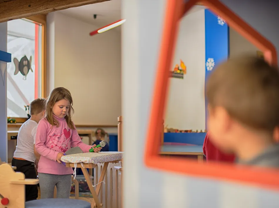 Child plays in cozy ski kindergarten with wooden toys at a family-friendly mountain station