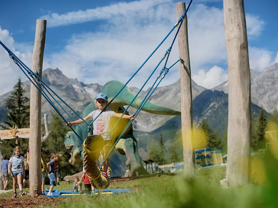 Mädchen schwingt auf Seilschaukel im Spielpark Klausberg mit Panorama der Zillertaler Alpen
