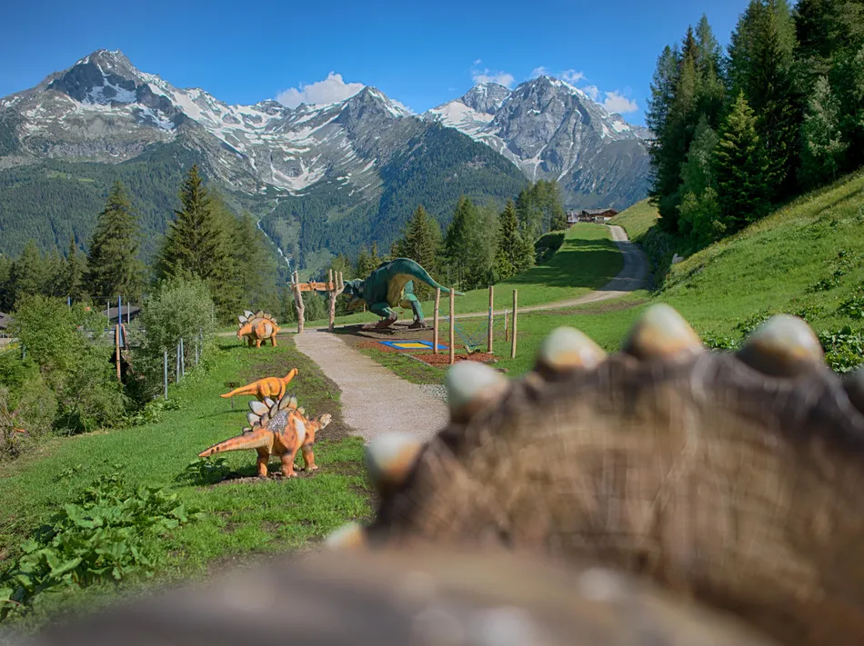 Klaussi's Dinopark am Klausberg: Dinosaurier-Figuren auf Almwiese vor beeindruckendem Bergpanorama