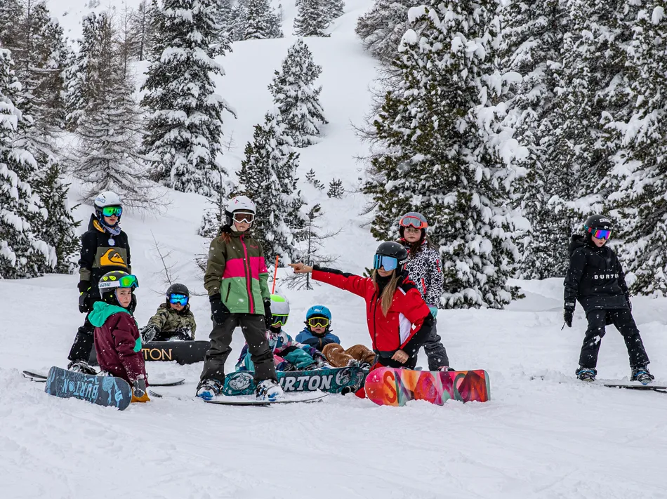 Children's snowboard lesson with instructor among snow-covered trees in Skiworld Ahrntal