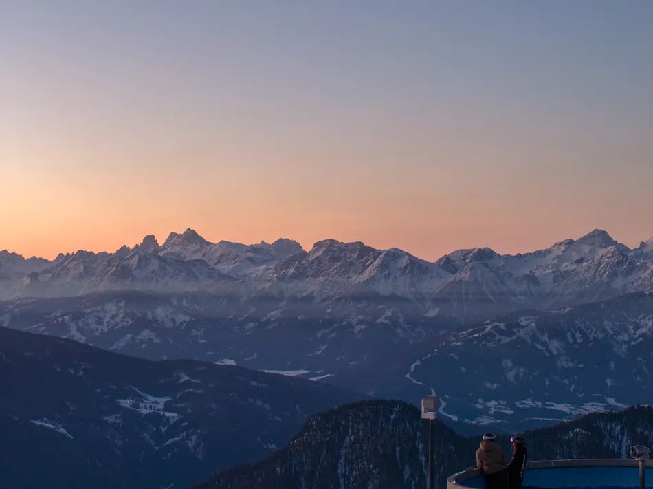 Sonnenaufgang über Dolomiten mit zwei Personen auf der Aussichtsplattform am Klausberg