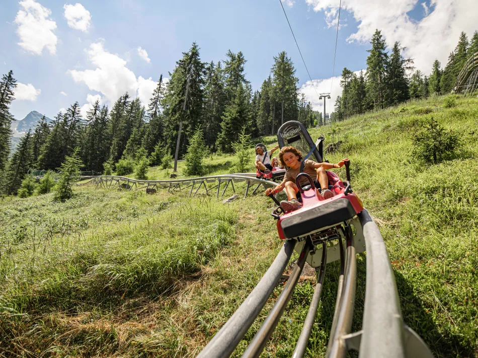 Pista alpina Klausberg-Flitzer con bambino e padre su prato alpino verde, Skiworld Ahrntal