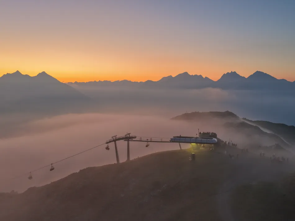 Cabine della funivia al Klausberg al tramonto con mare di nebbia e vette alpine